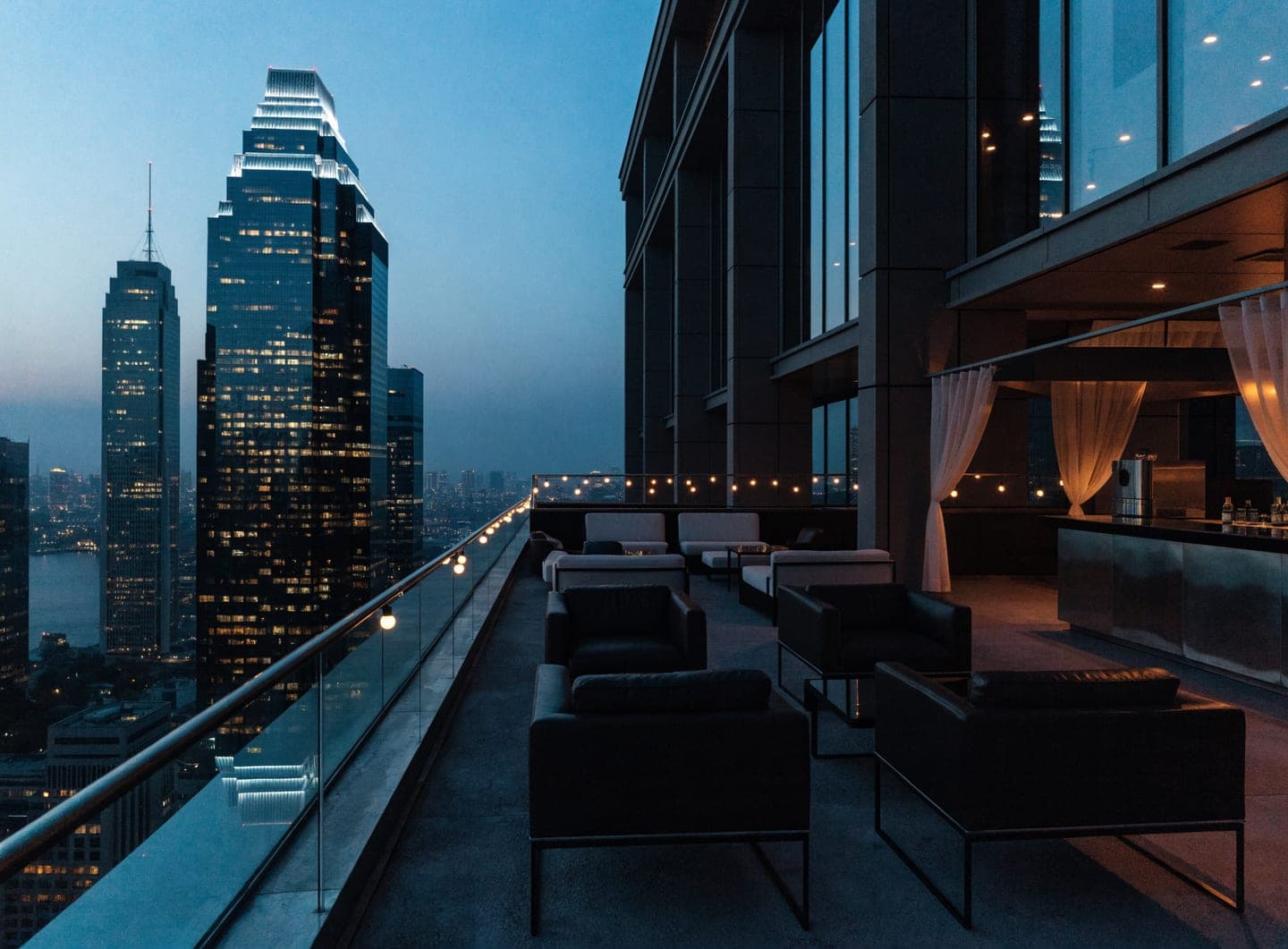 Rooftop terrace of a city hotel at dusk with skyline views